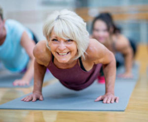 older woman holding plank on yoga mat