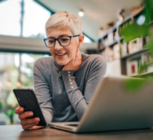 older woman at desk with laptop and phone