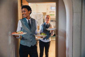 Two waiters coming out of a kitchen