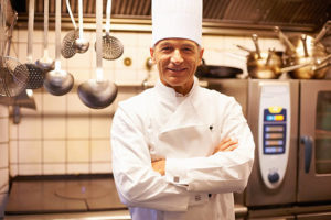 chef smiling and posing among kitchenware