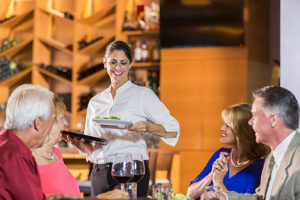 waitress serving food to senior couples